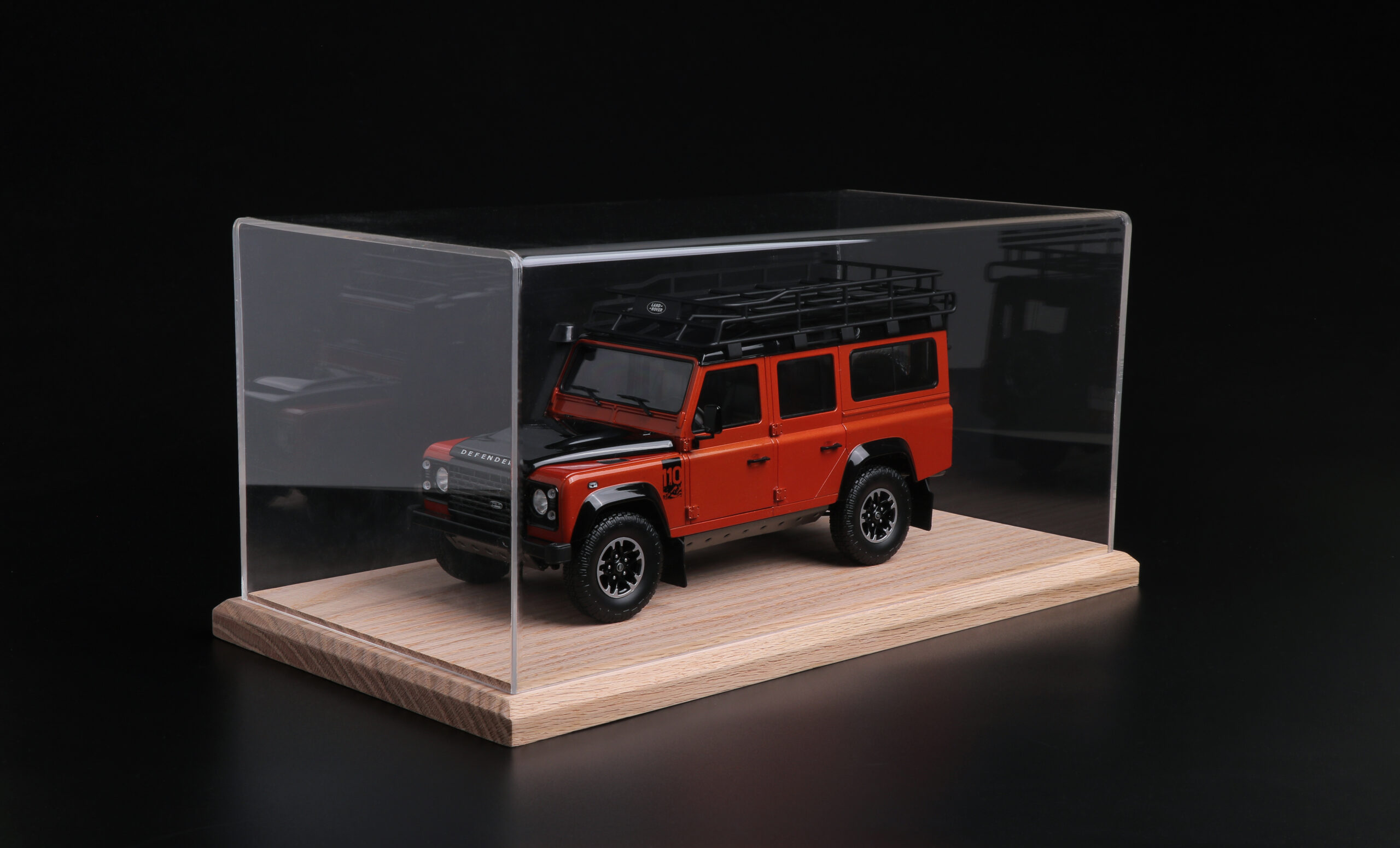 Red Land Rover Defender model car in a tabletop display case