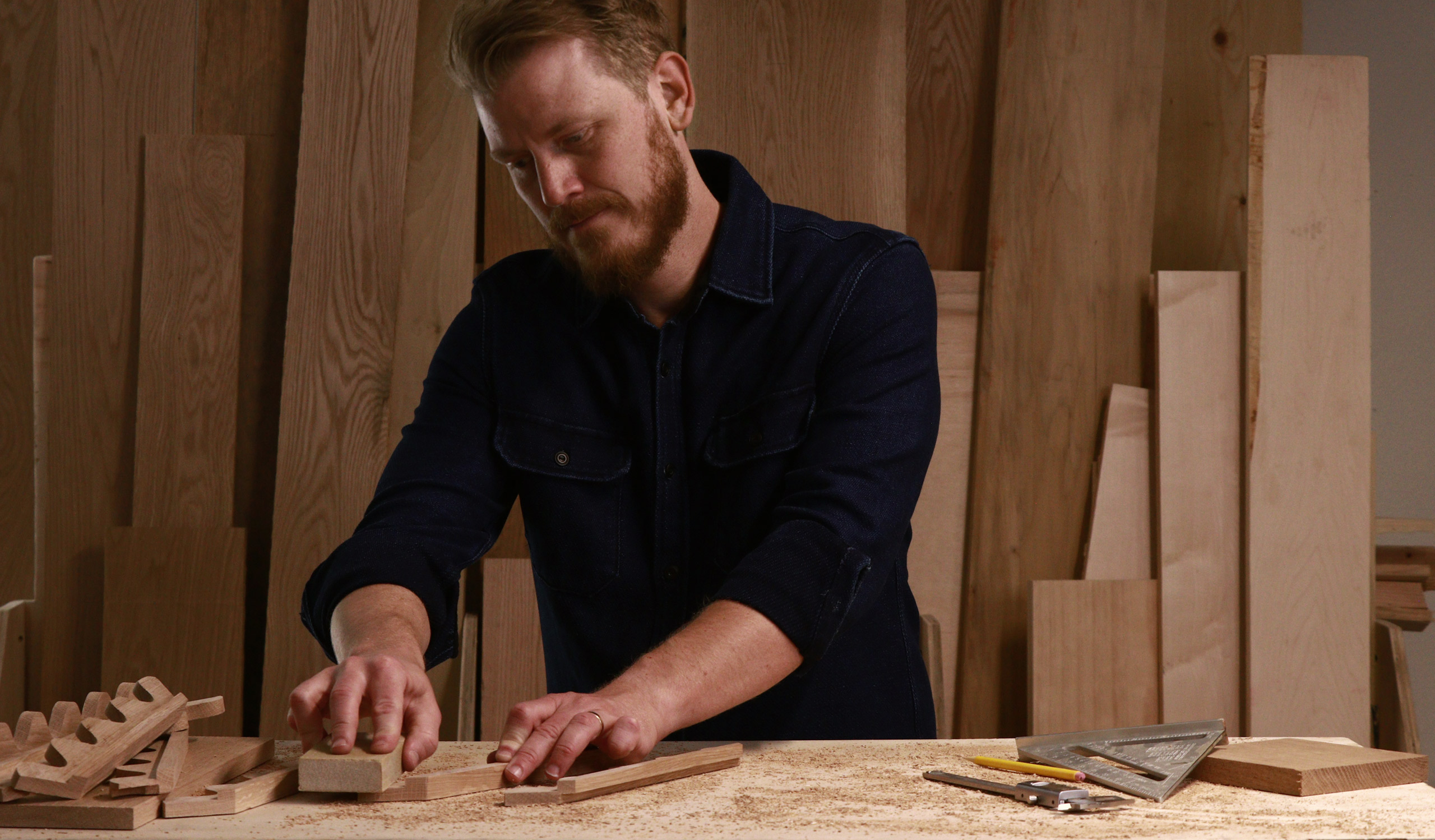 Craftsman measuring and cutting wood pieces at a workbench