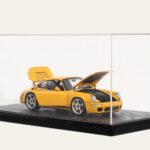 Black tabletop display case with a yellow Porsche model car, doors open