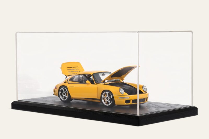 Black tabletop display case with a yellow Porsche model car, doors open