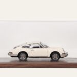 Cream Porsche model car in a walnut tabletop display case, side view