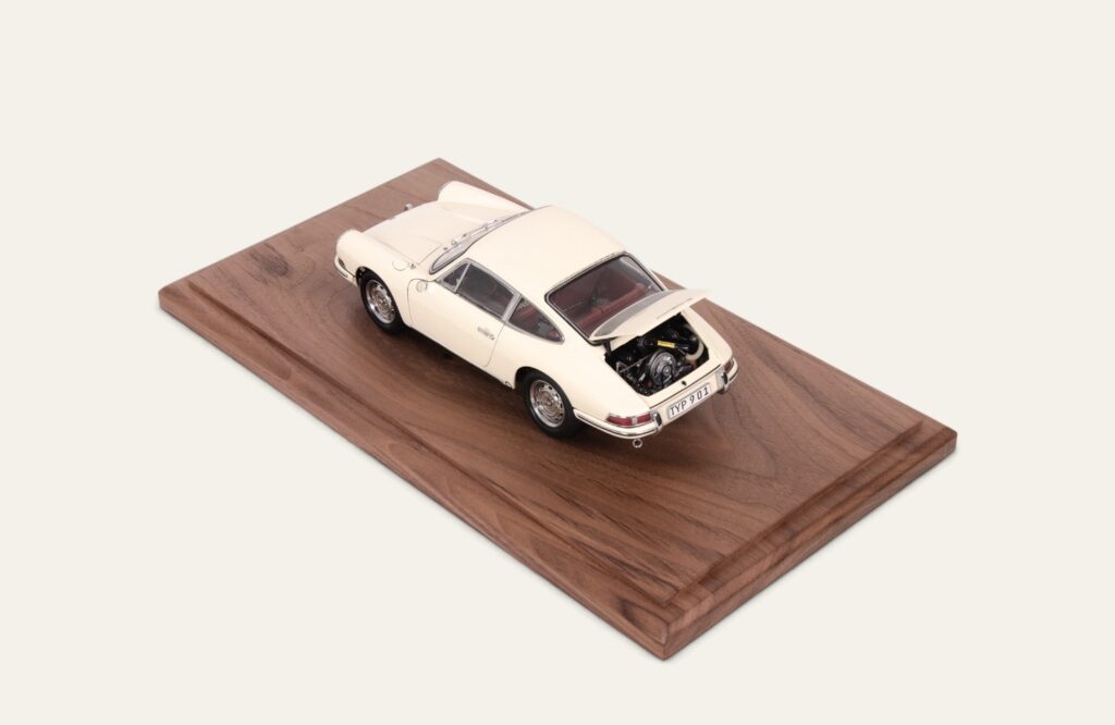 Cream Porsche model car on a walnut base, rear three-quarter view