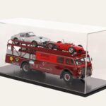 Ferrari car transporter model loaded with a race car in a black-based display case